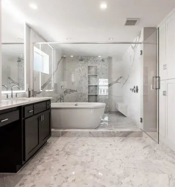 Minnesota bathroom remodel with full marble tile, freestanding soaking tub, glass shower enclosure, and dark double vanity