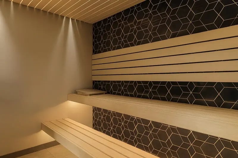 Custom home sauna with cedar bench seating, geometric black tile accent wall, and LED mood lighting in a Minnesota home