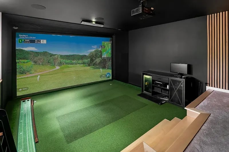 Indoor golf simulator with a large screen showing a virtual golf course
