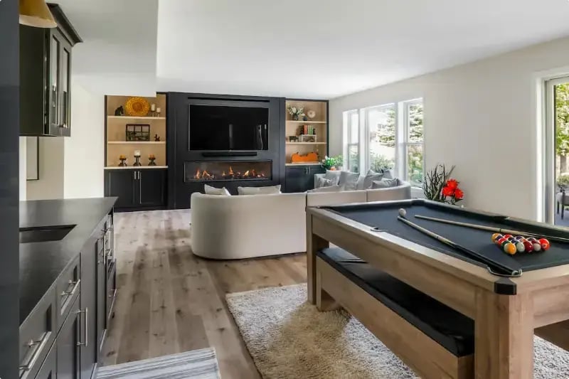 Finished basement entertainment room with pool table, linear fireplace, and built-in shelving remodeled by Titus Contracting