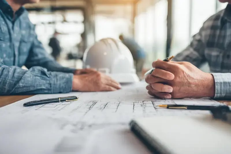Two contractors reviewing blueprints at a planning meeting for a Titus Contracting design-build project