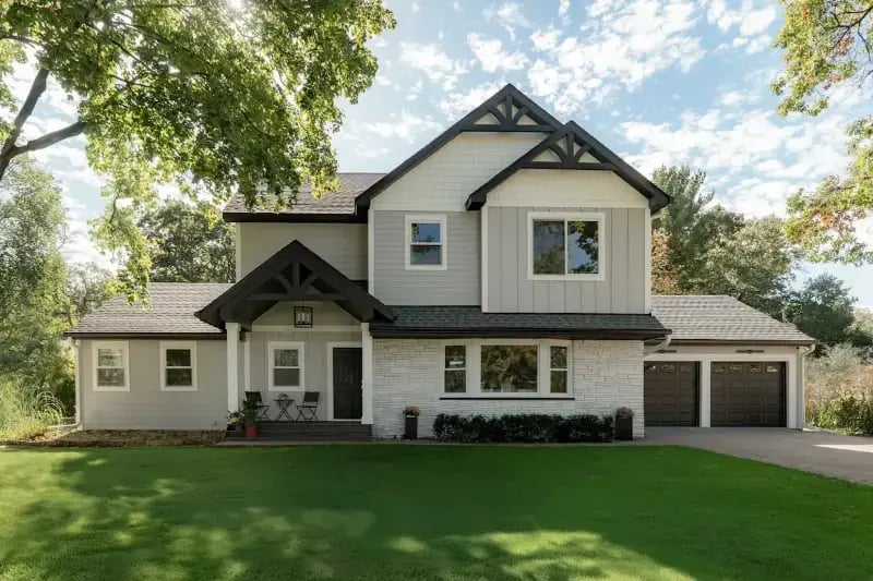 White craftsman-style home exterior with second story addition, board and batten siding, and attached garage remodeled by Titus Contracting