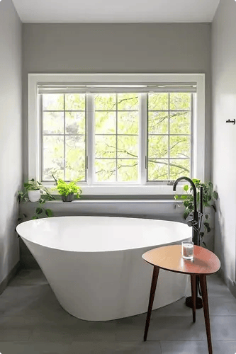 Freestanding soaking tub beneath large window with garden views in a Minnesota spa bathroom remodel