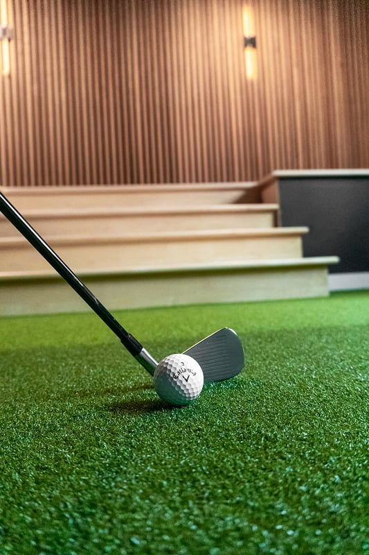 Golf club and ball on synthetic turf inside a custom Minnesota home golf simulator installation