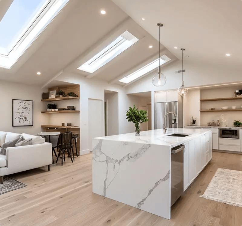 Minnesota kitchen remodel with vaulted skylight ceiling, waterfall marble island, white cabinetry, and open concept living area