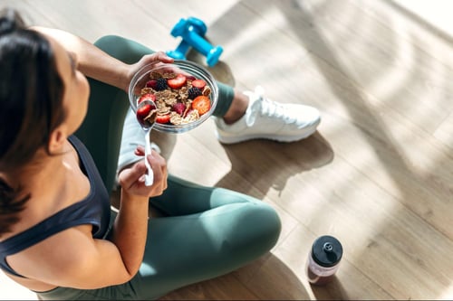 person eating a smoothie bowl in their home gym