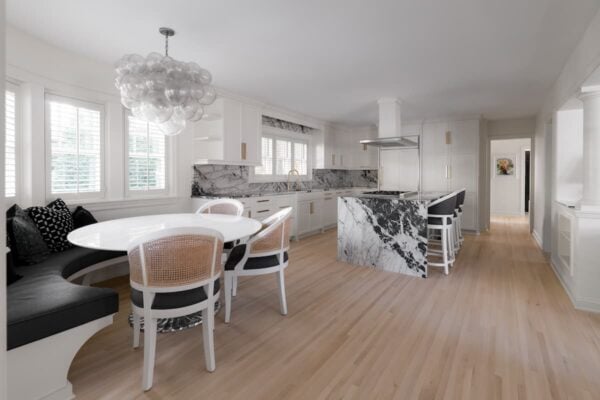 a kitchen and dining area with an open concept plan. the dining area has a built-in bench. The kitchen has striking, black-and-white marbled countertops.