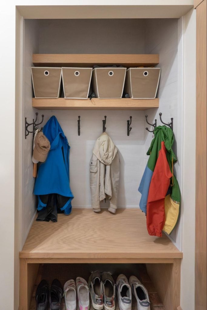 A cubby with hooks, shelving, and storage inside a mudroom.