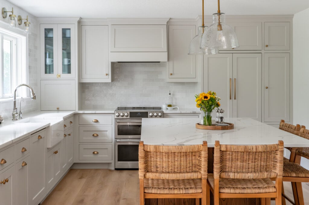 a kitchen with white cabinets and countertops and warm wooden furniture accents