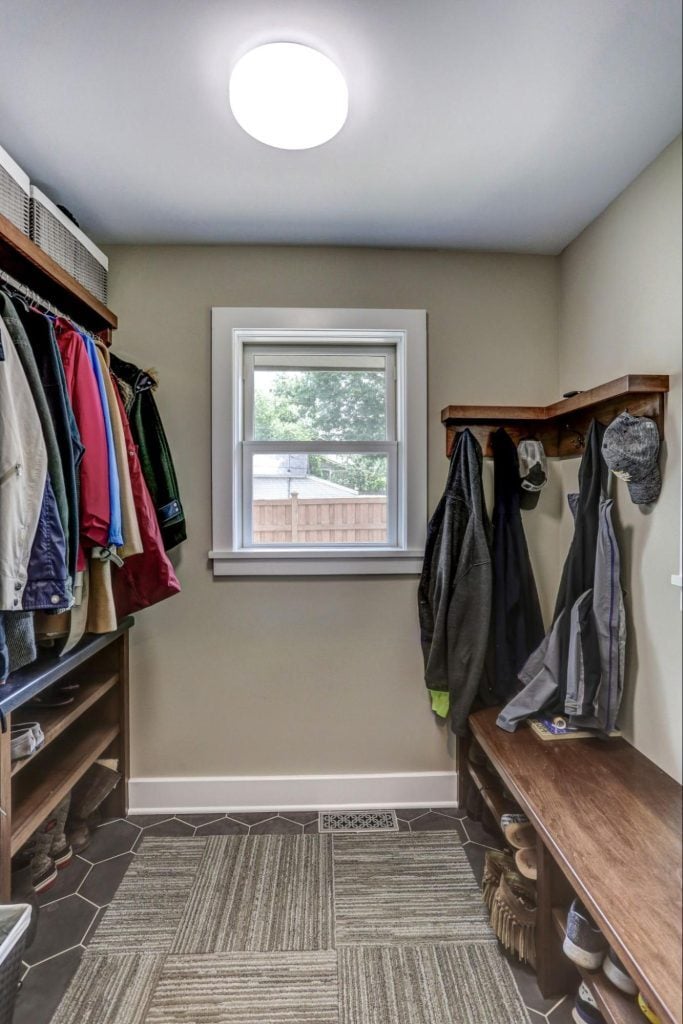 a mudroom with built-in shelving, a window, and a large overhead light.