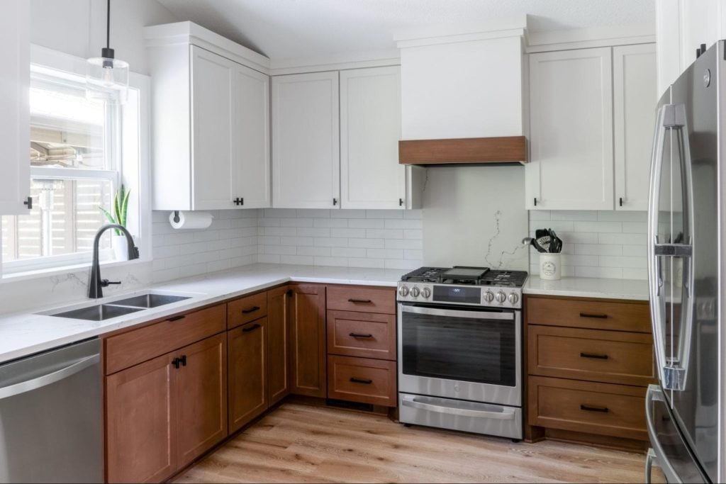 a recently remodeled kitchen. all of the counters are a warm, dark brown. The cabinets are a painted white, and above the stove is a large-scale marble backsplash. 