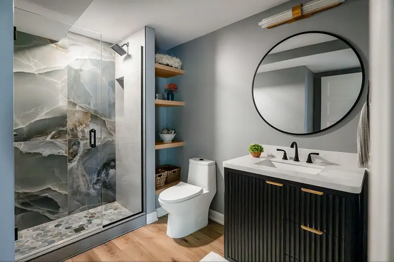 Minnesota basement bathroom remodel with dramatic marble slab shower, fluted black vanity, and round mirror