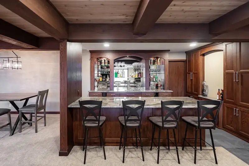 Minnesota basement remodel with custom cherry wood wet bar, granite island, and backlit glass display cabinets
