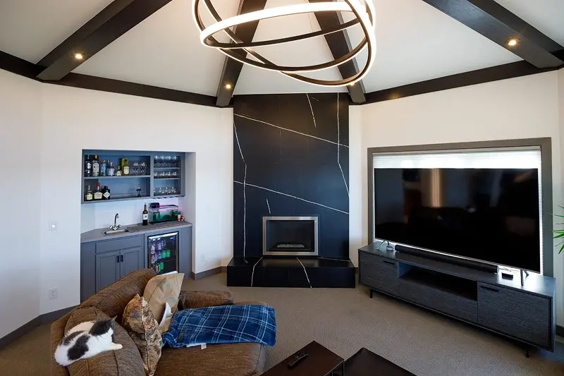 Minnesota lower level remodel with black marble fireplace surround, wet bar, and custom beam ceiling with statement chandelier