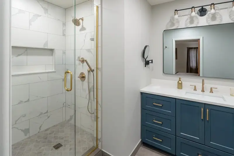 Minnesota bathroom remodel with teal shaker vanity, gold fixtures, and marble tile walk-in shower