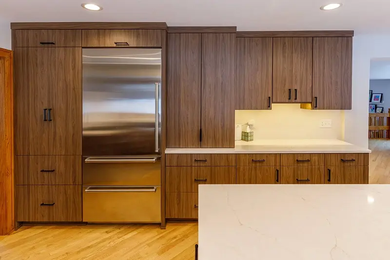 Minnesota kitchen remodel with flat-front walnut cabinetry, integrated refrigerator, and quartz countertops