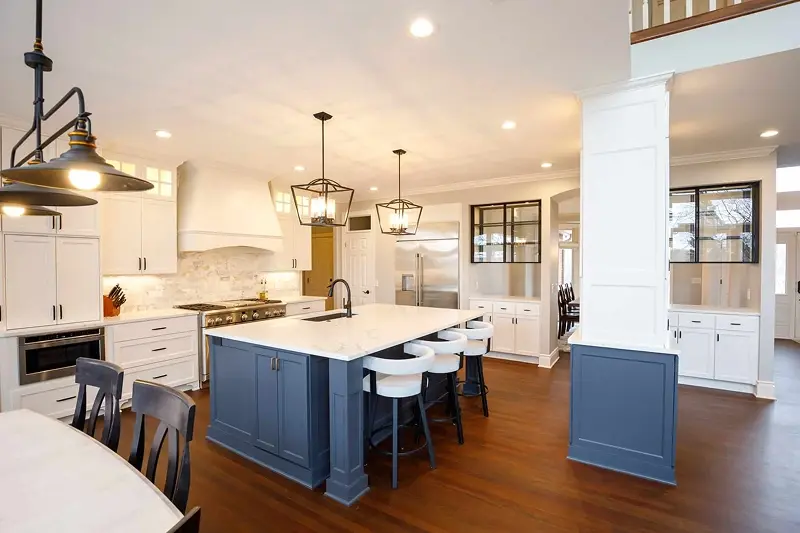 Minnesota kitchen remodel with white cabinetry, navy blue island, marble countertops, and lantern pendant lights