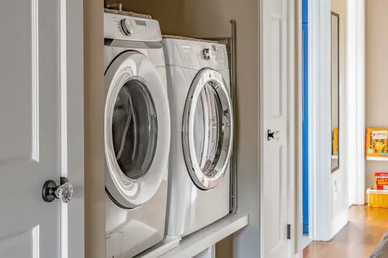 Laundry closet renovation with stacked washer and dryer and white shelving