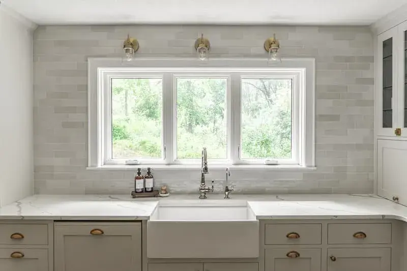 full wall marble subway tile backsplash, apron front sink and gold accent hardware