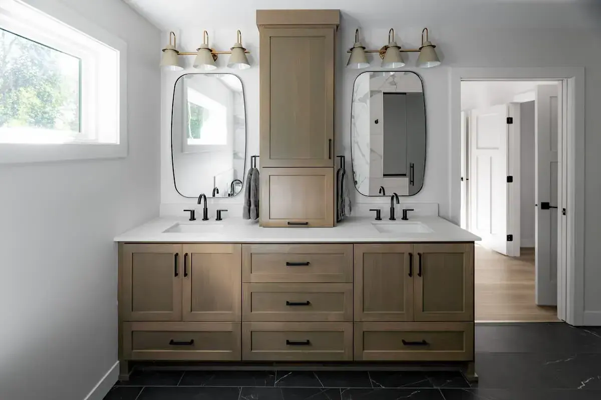 wood tone vanity with double sinks and middle cabinet