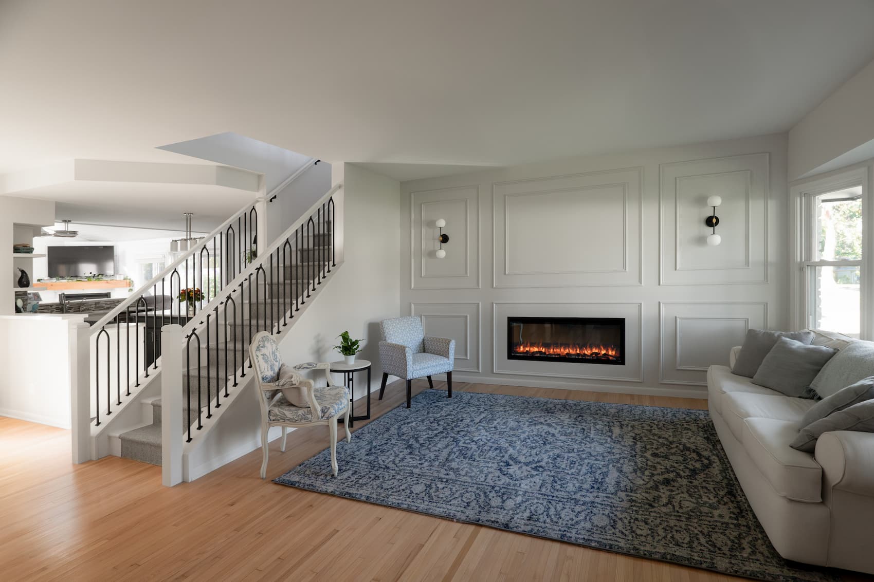downstairs area with stairs leading up a level. The sage green accent wall features wainscoting and a built-in fireplace.