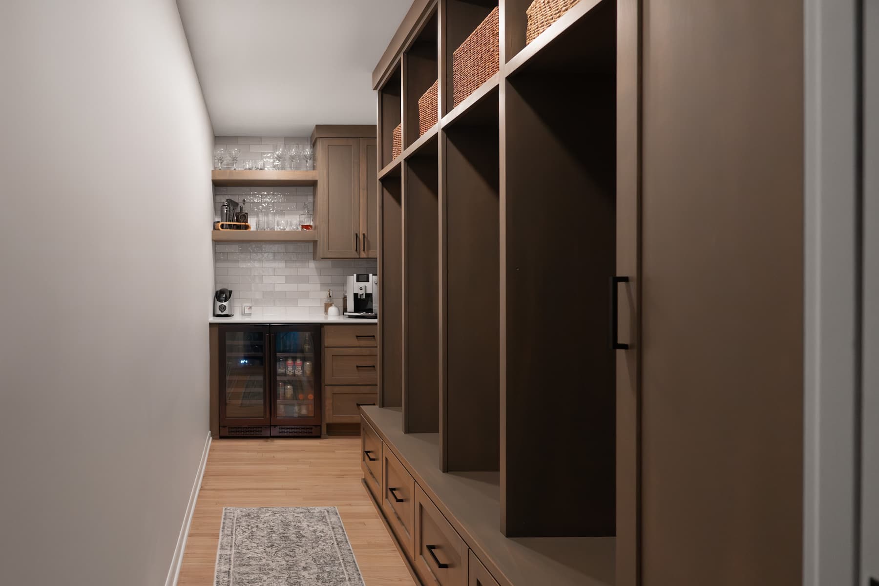 a mudroom with built-in shelves. against the far wall, leading into the kitchen, is a custom coffee bar with mini fridge.