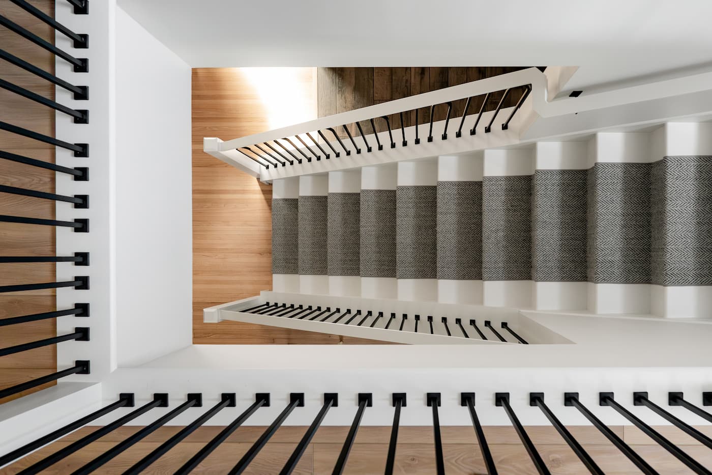 view from upper landing of staircase onto staircase. white wood is fitted with carpeting for comfort.
