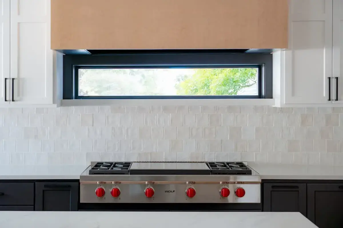 Black lower cabinets with white uppers. Wood hood on large wolf range.