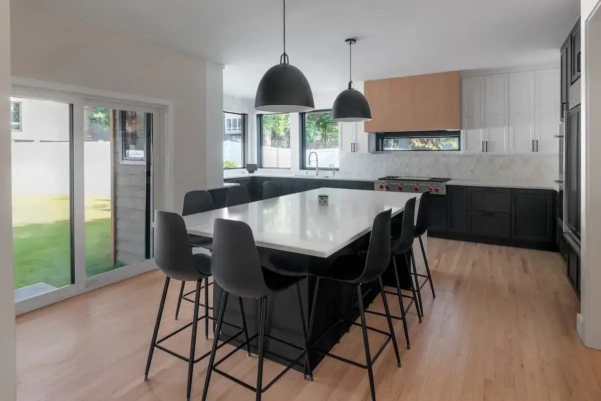 Black lower cabinets with white uppers. Wood hood on large wolf range. oversized island seating