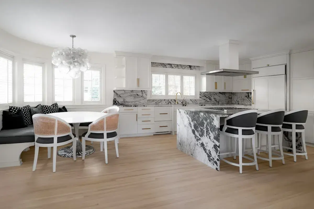 a kitchen and dining area with an open concept plan. the dining area has a built-in bench. The kitchen has striking, black-and-white marbled countertops.