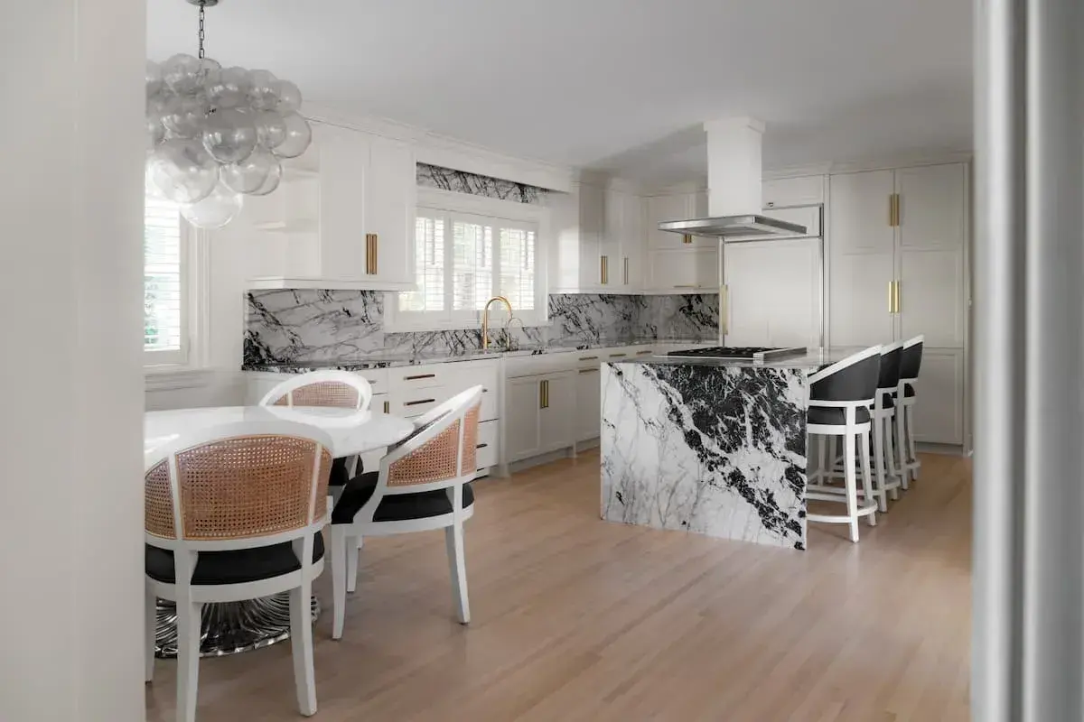 a kitchen and dining area with an open concept plan. the dining area has a built-in bench. The kitchen has striking, black-and-white marbled countertops.