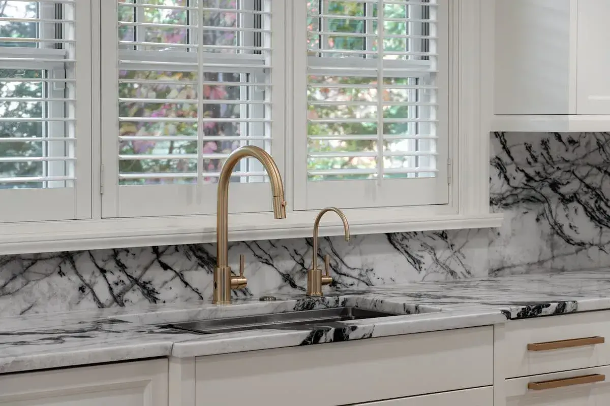 a kitchen and dining area with an open concept plan. the dining area has a built-in bench. The kitchen has striking, black-and-white marbled countertops.