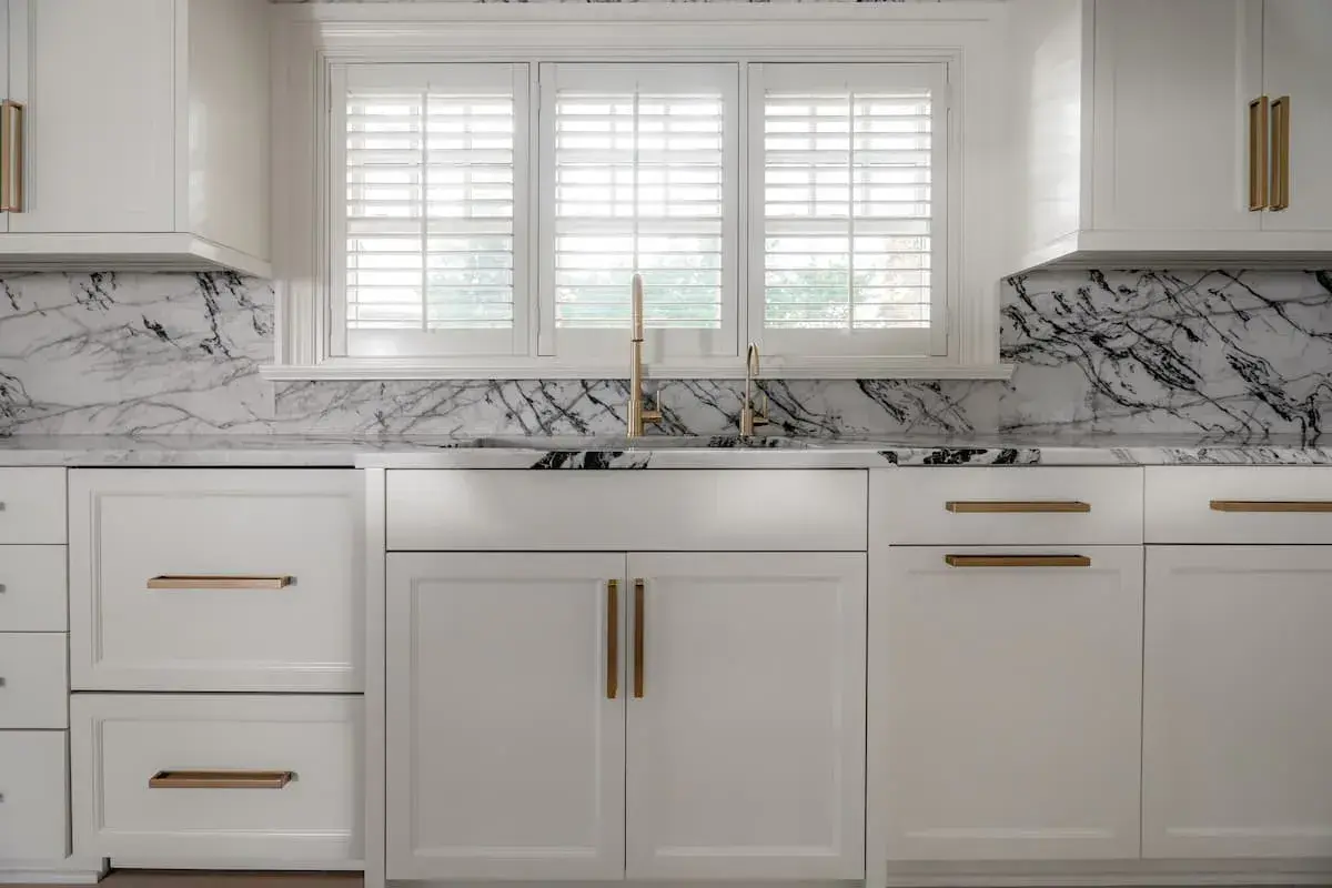 a kitchen and dining area with an open concept plan. the dining area has a built-in bench. The kitchen has striking, black-and-white marbled countertops.
