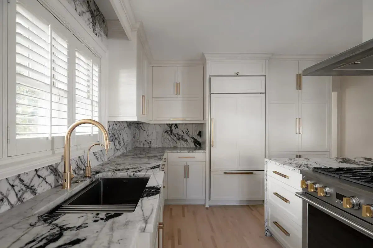 a kitchen and dining area with an open concept plan. the dining area has a built-in bench. The kitchen has striking, black-and-white marbled countertops.