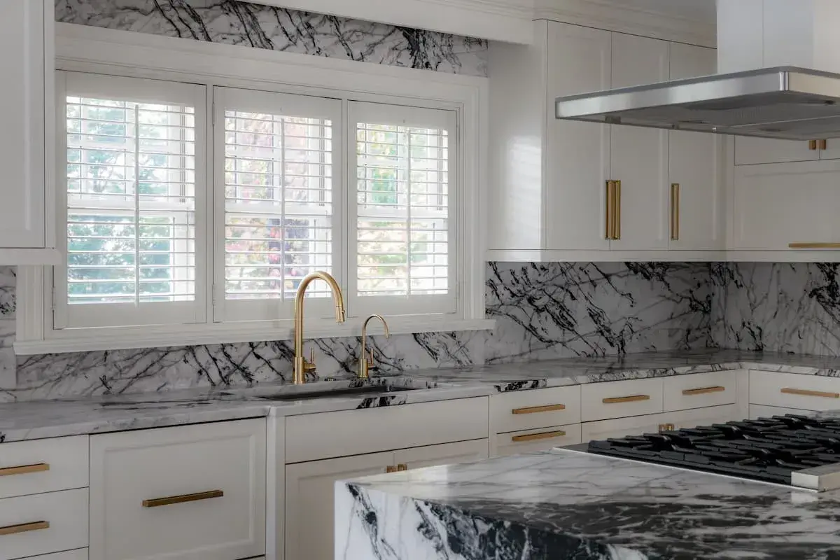a kitchen and dining area with an open concept plan. the dining area has a built-in bench. The kitchen has striking, black-and-white marbled countertops.