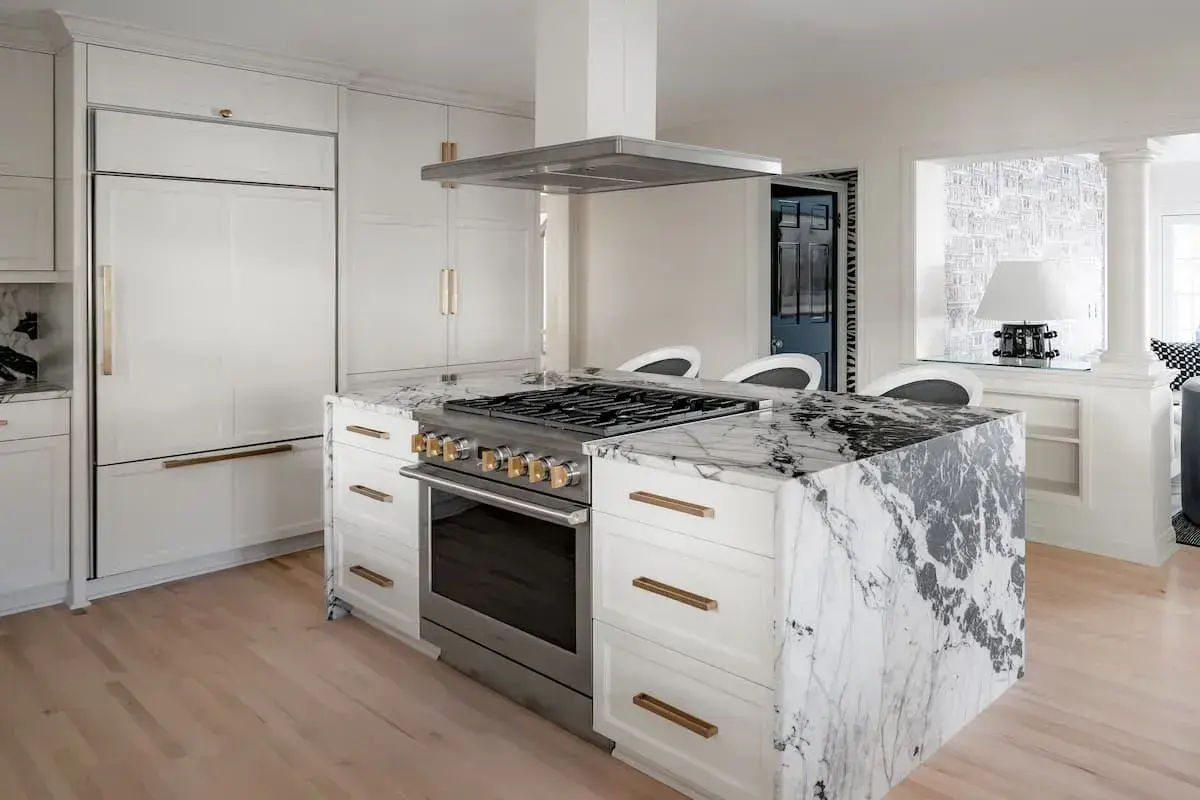 marble wrapped kitchen island with stove and hood gold accents