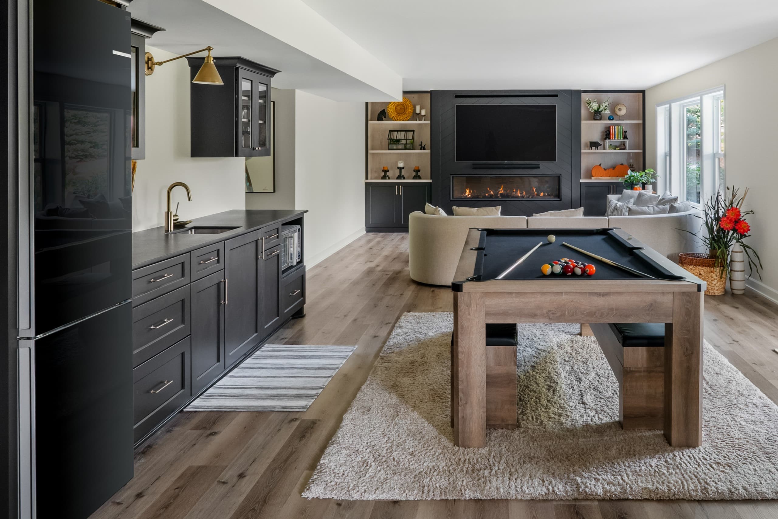 a view of a basement with a kitchen area, pool table, and full wall built-in