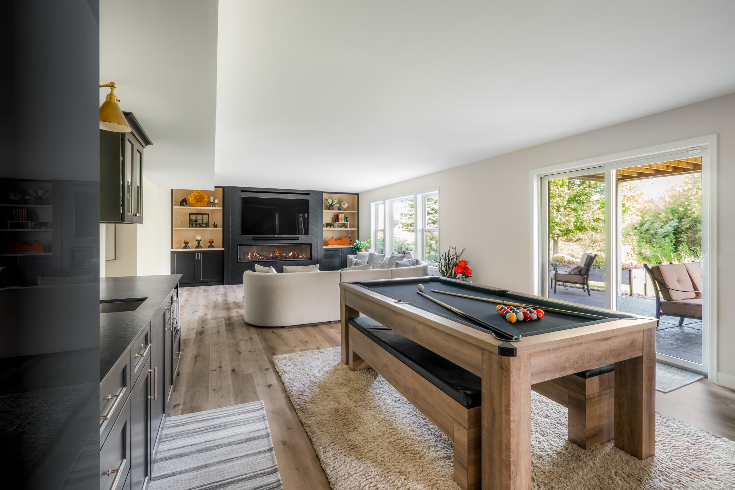 a view of a basement with a kitchen area, pool table, and full wall built-in