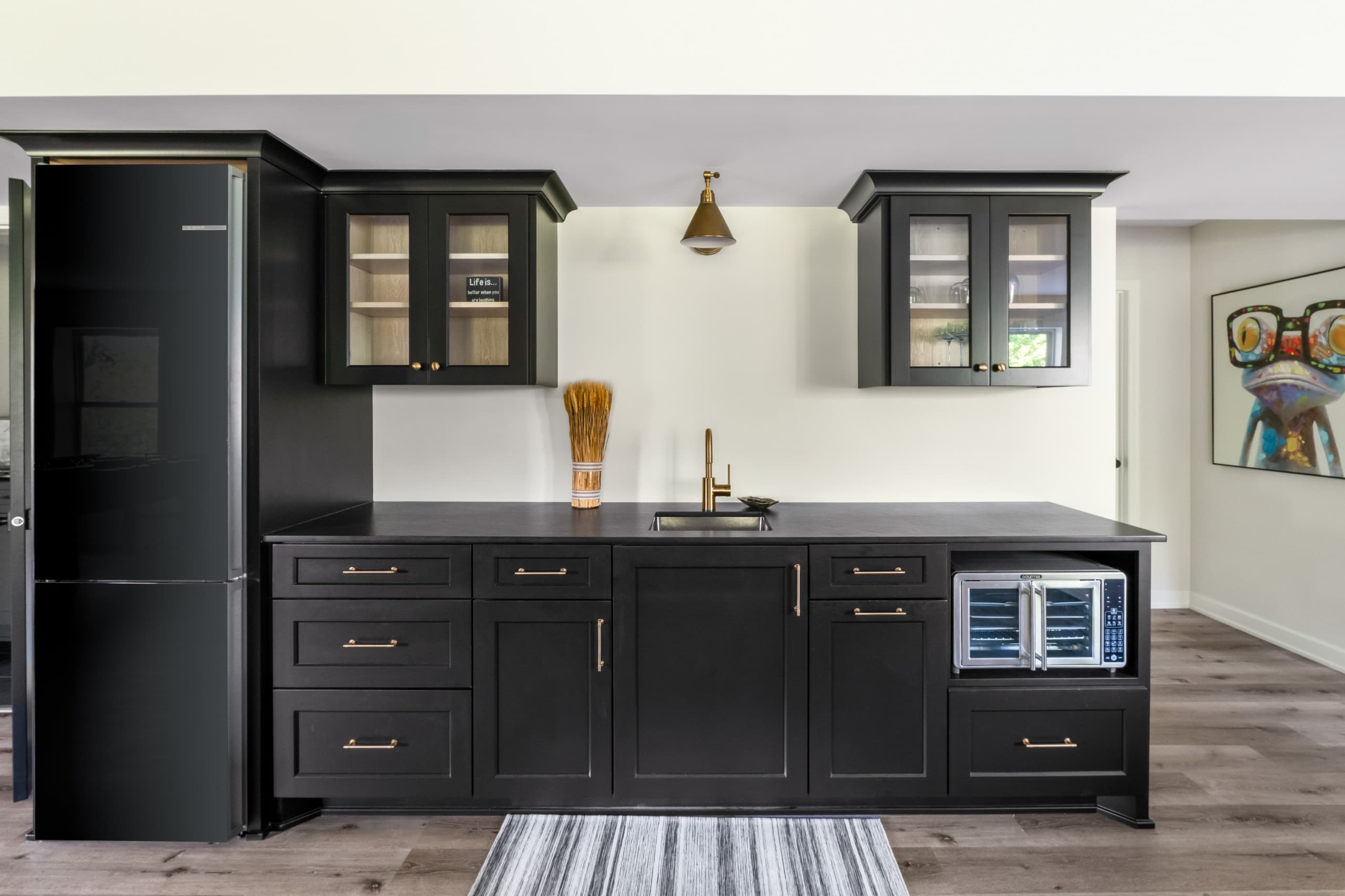 a kitchenette in a basement with dark cabinets