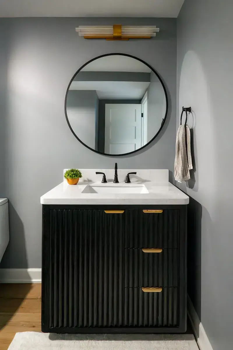 scalloped black vanity with gold hardware and large round mirror