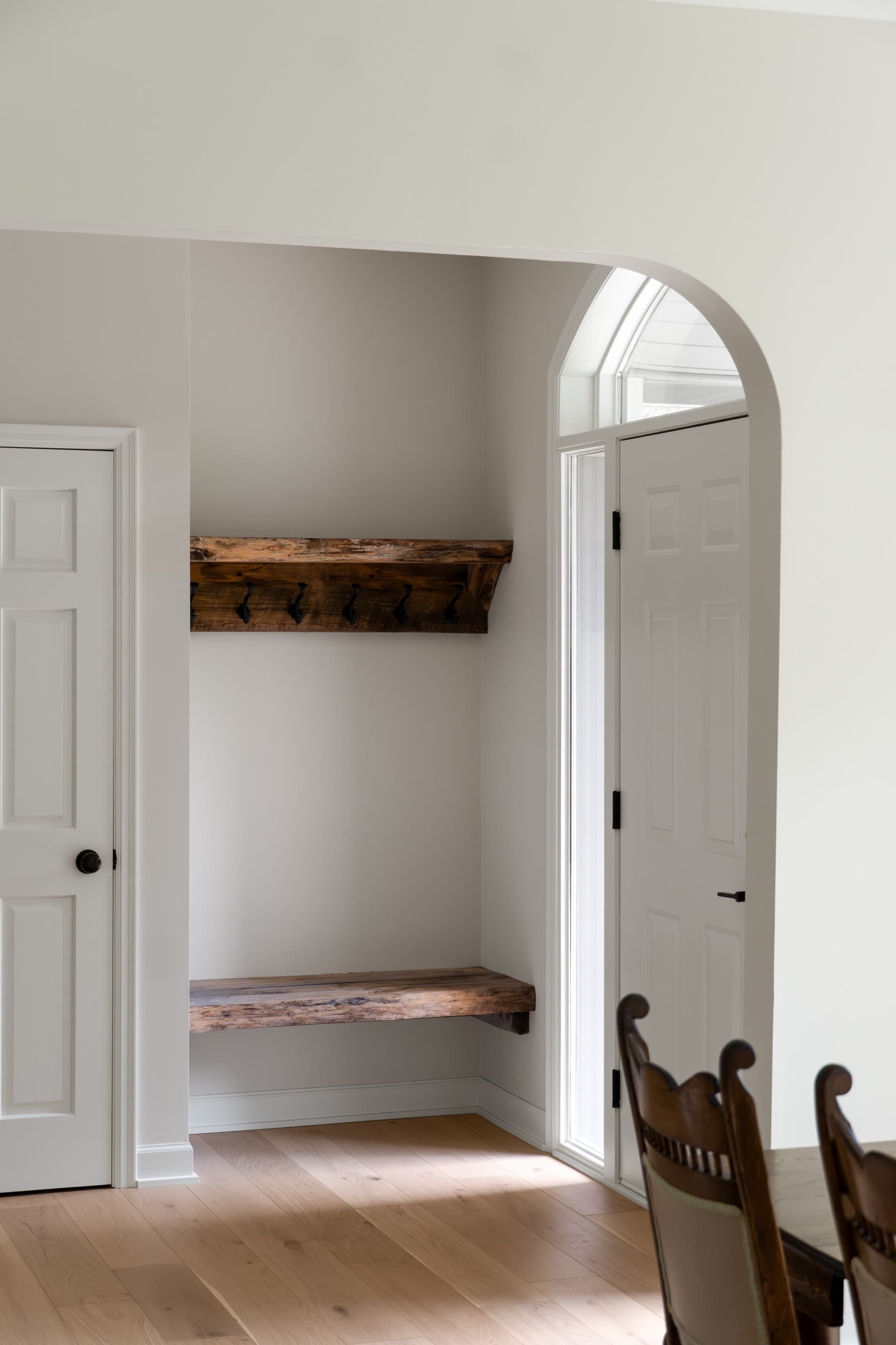 a home entryway with bespoke, rough-hewn wooden bench and clothing rack