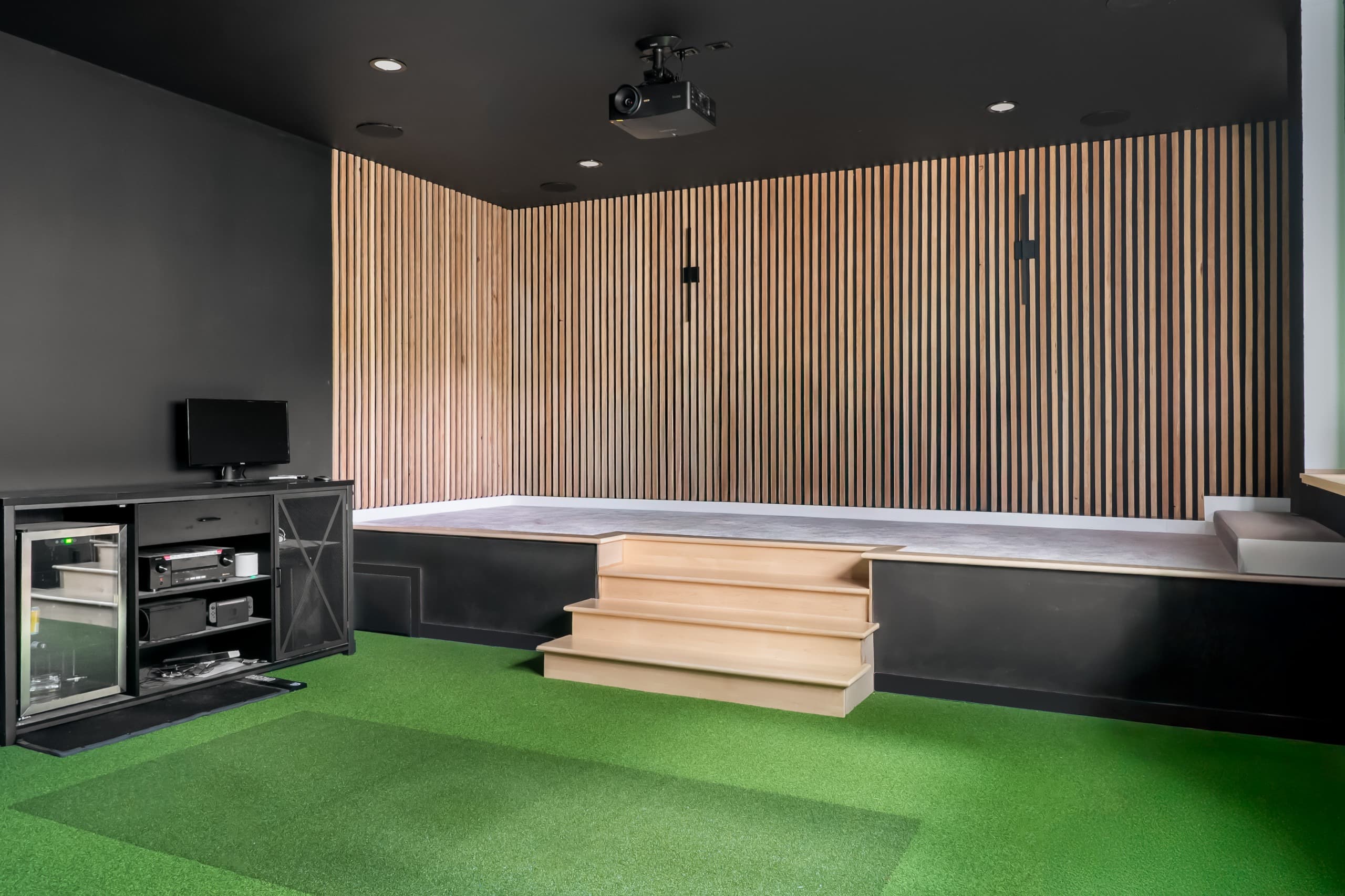 a golf simulator room with green grass and digital screen