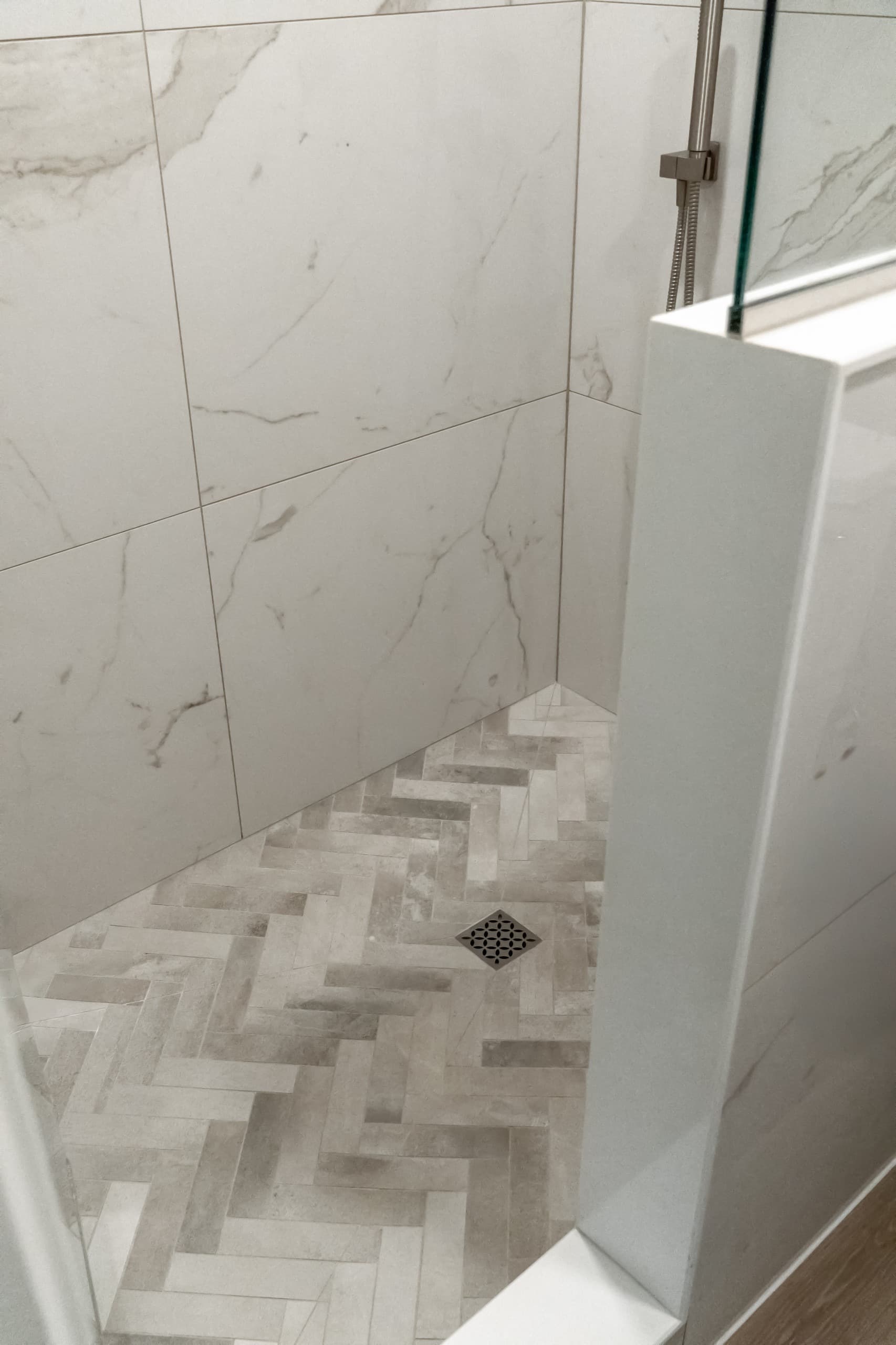 a close up of a shower with large scale marble tiles