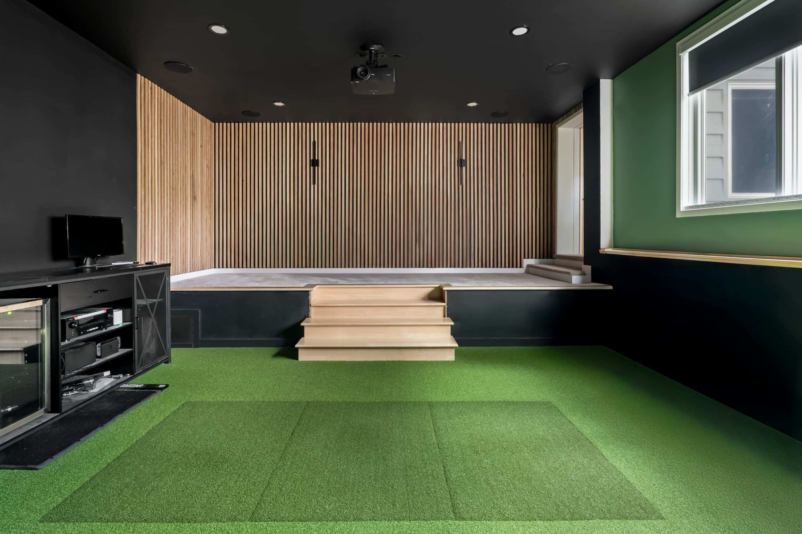 a golf simulator room with green grass and digital screen