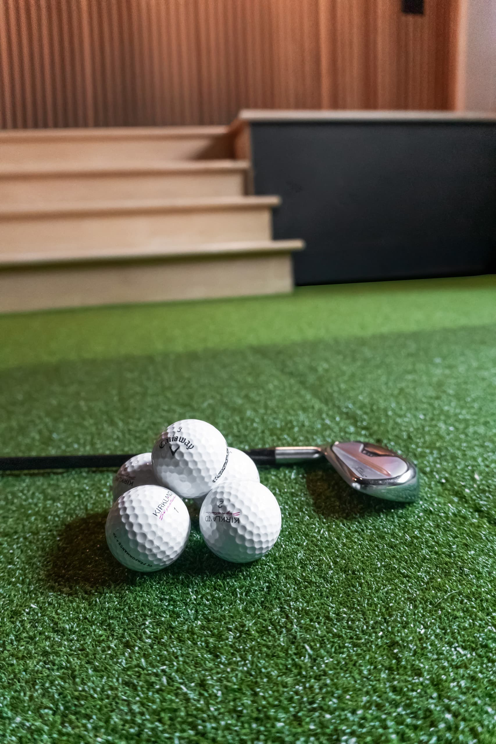 a golf simulator room with green grass and digital screen