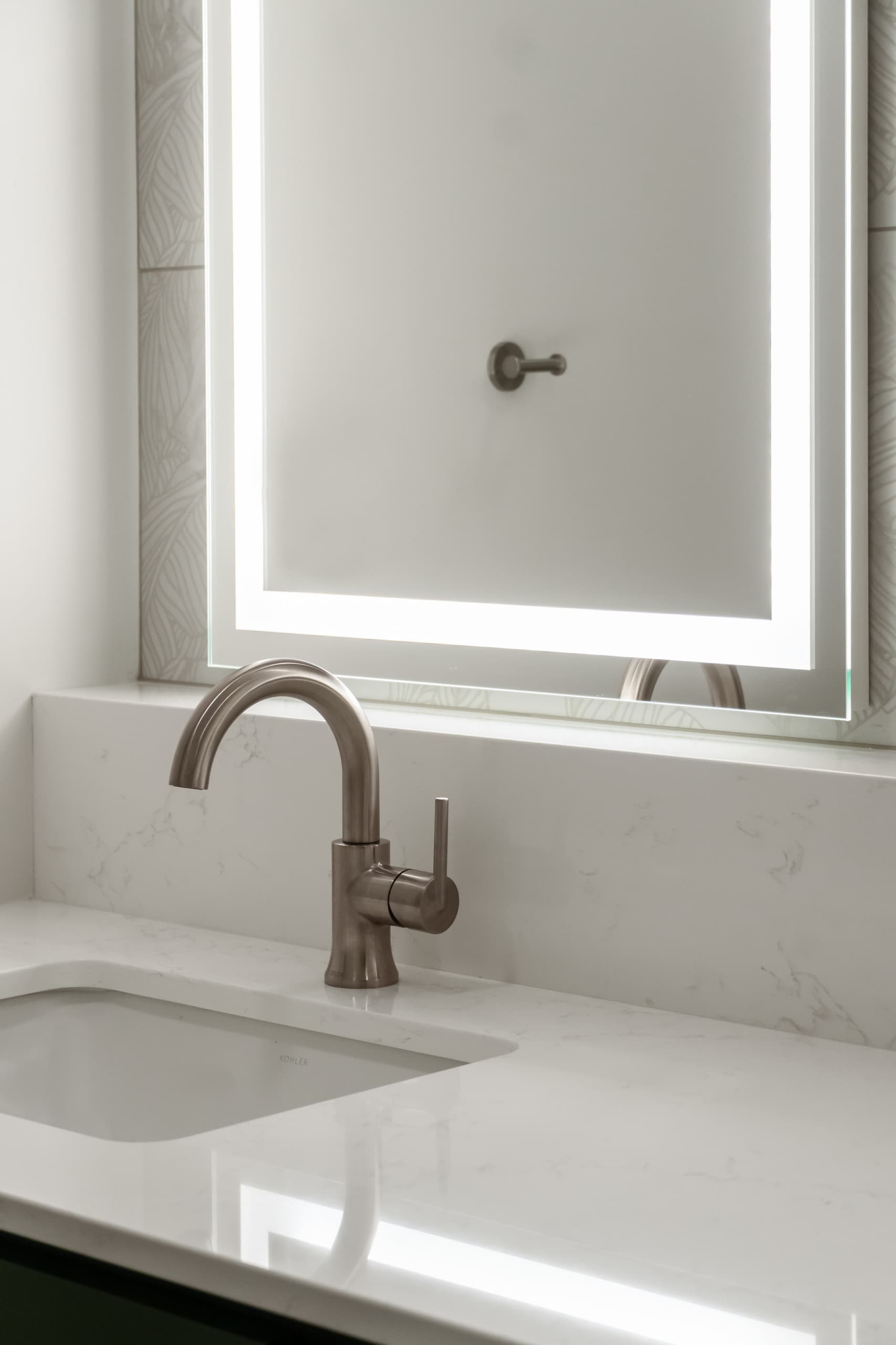 a bathroom with dark green vanity, white countertops, and oversized warm gray stone tiles
