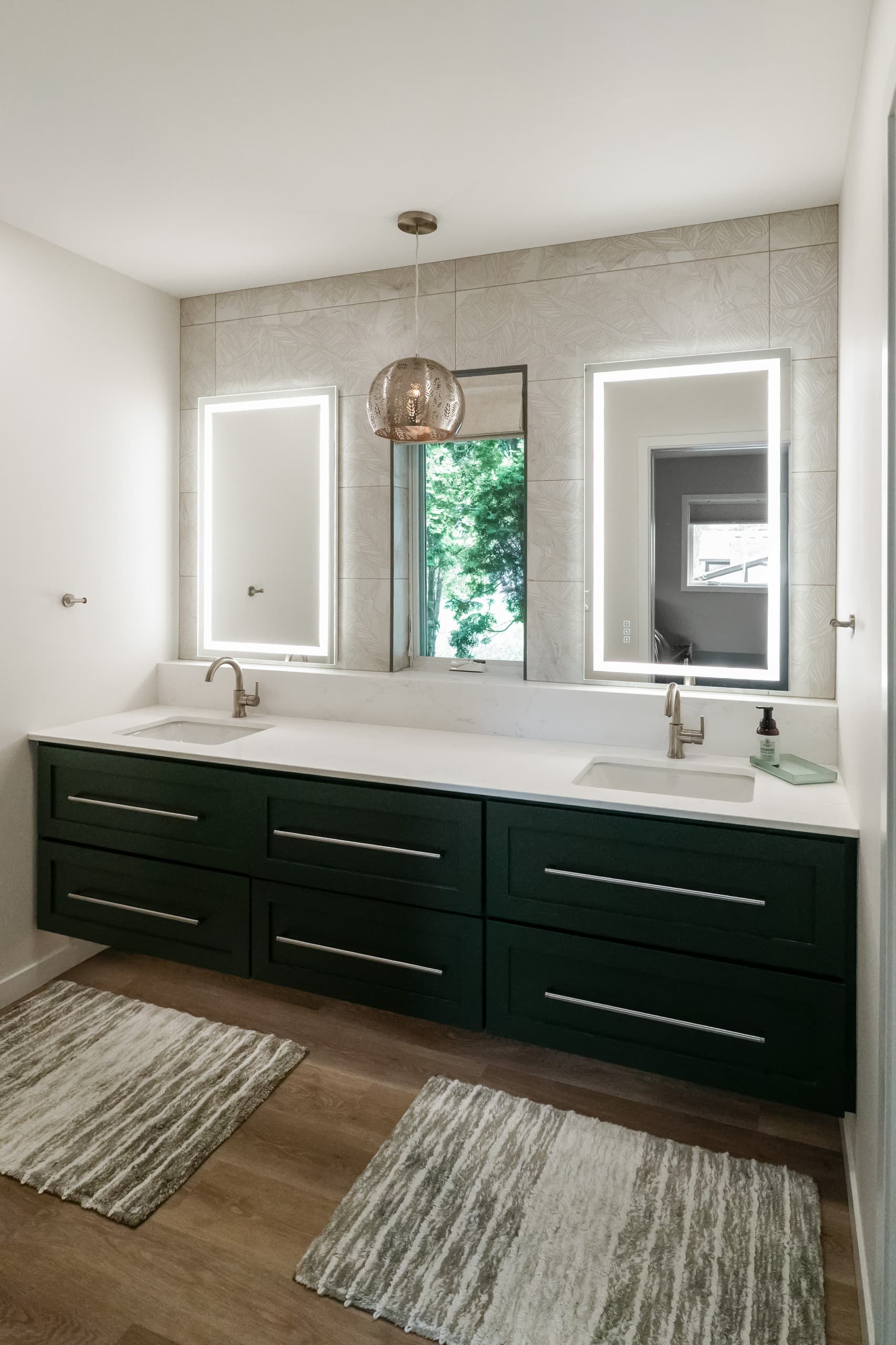 a bathroom with dark green vanity, white countertops, and oversized warm gray stone tiles
