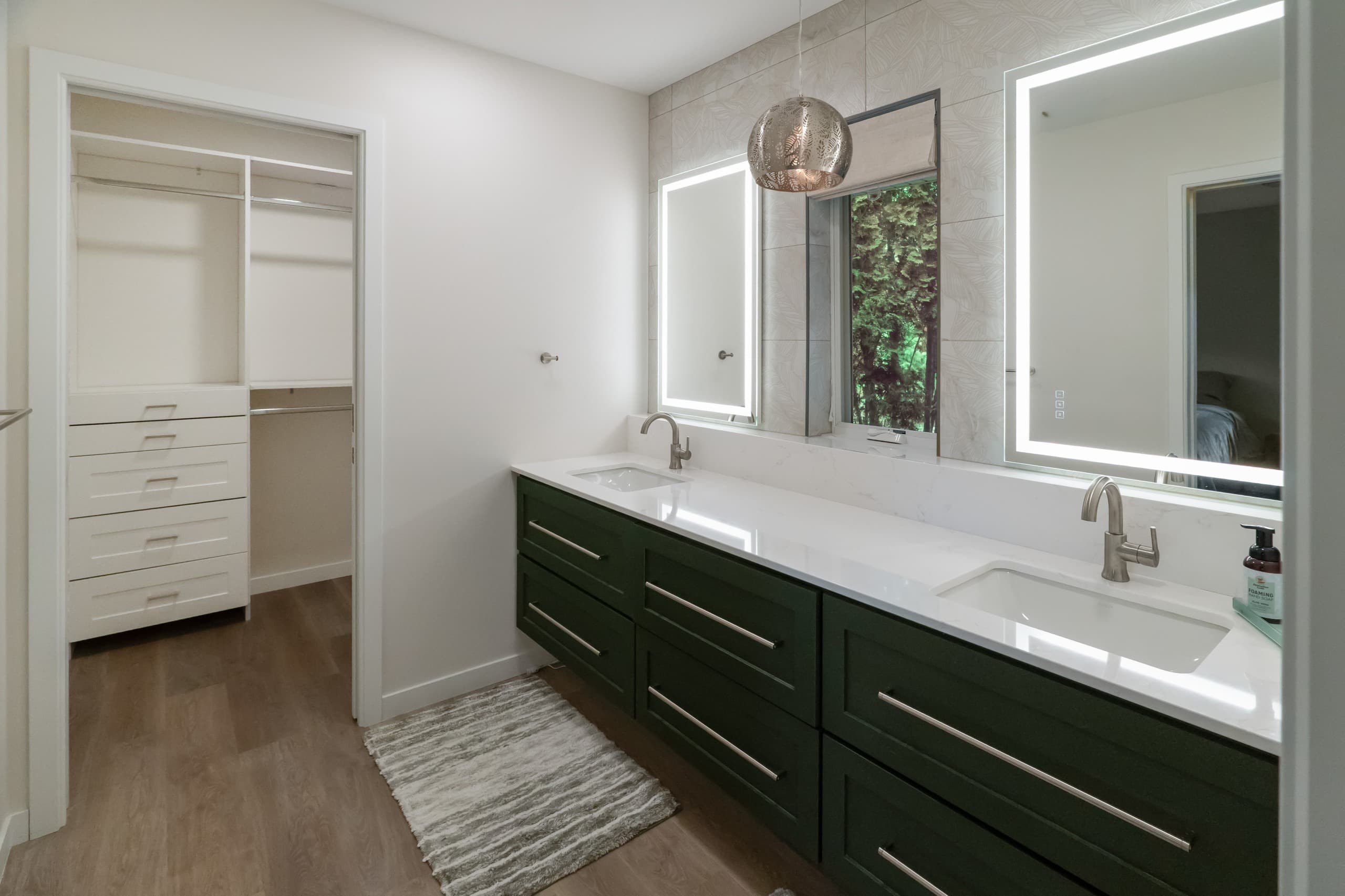 a bathroom with dark green vanity, white countertops, and oversized warm gray stone tiles
